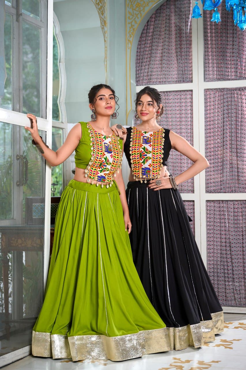 Two women wearing traditional outfits with intricate designs in a decorated room.